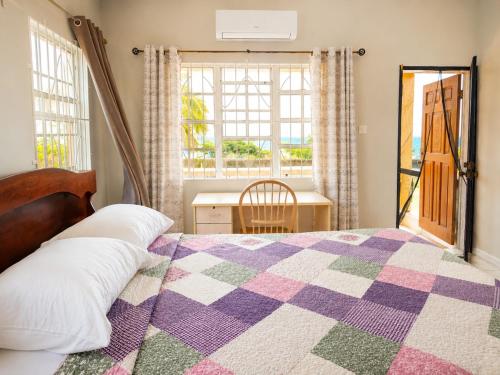 a bedroom with a bed and a window and a desk at Ocean Breeze Retreat in Basseterre