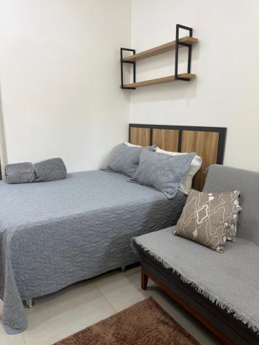 a bedroom with a bed and a couch and a shelf at Loft bem localizado na cidade! in Boa Vista