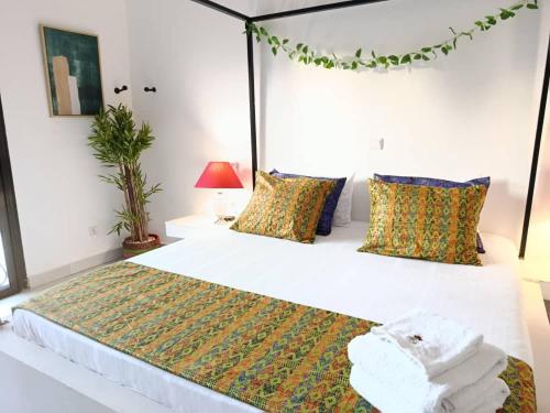 a bedroom with a large white bed with colorful pillows at Villa DOUDOU in Somone