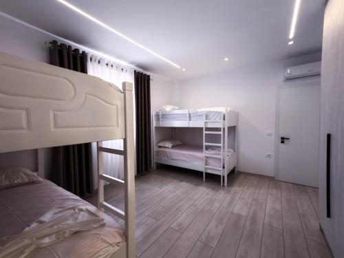 a bedroom with two bunk beds and a wooden floor at Lakeside Palms in Tirana