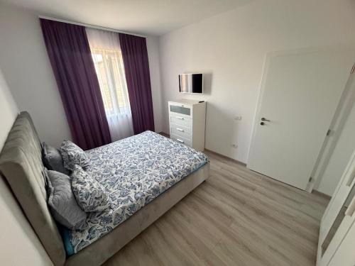 a bedroom with a bed and a dresser and a window at C&A Apartment in Giroc