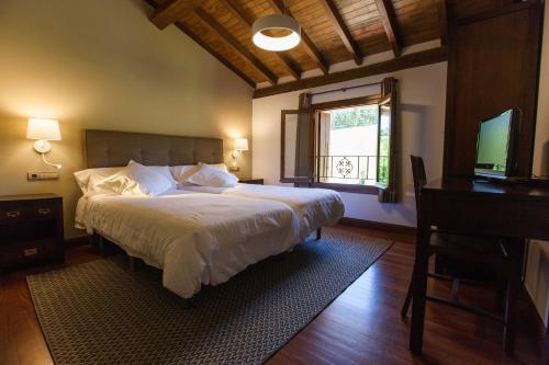 a bedroom with a large bed and a television at Casa Rural Arregi in Oñate