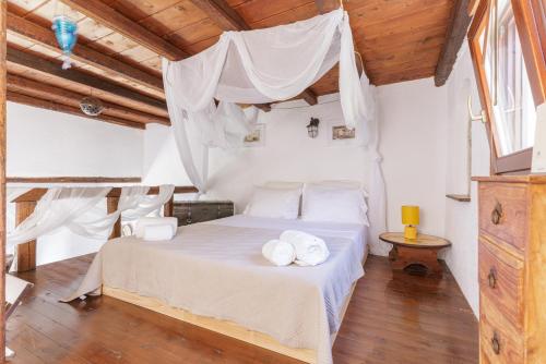 a bedroom with a bed with white sheets and pillows at Pasithea Sunset in Milopótamos