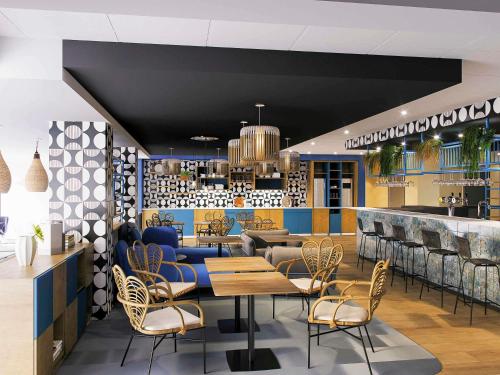 a restaurant with tables and chairs and a bar at Ibis Styles Miramas in Miramas