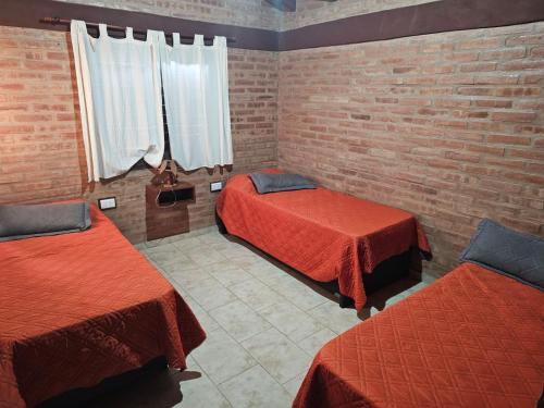 a room with two beds and a brick wall at Al pie de la Sierra in Pueblito