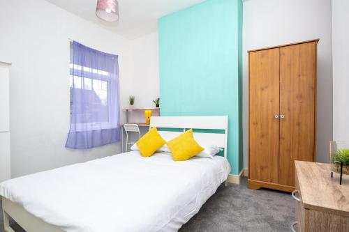 a bedroom with a white bed with yellow pillows at 2Bd Mid Terrace Close To Station in Stoke on Trent