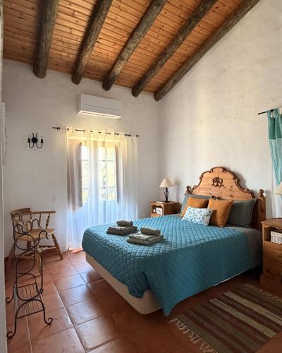 a bedroom with a bed with a blue comforter at Monte da Azinheira in Ourique
