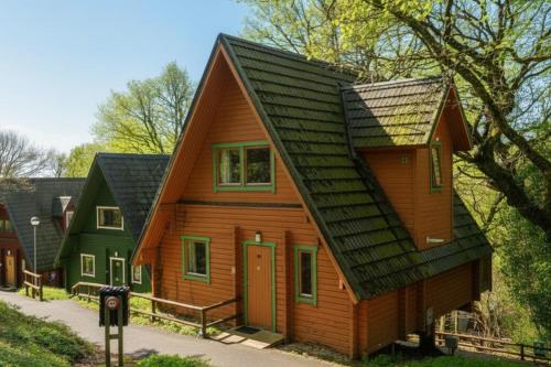 a small wooden house with a black roof at Scandi Style Bracken Lodge with Private Decking Sleeps 6 in Chudleigh Knighton