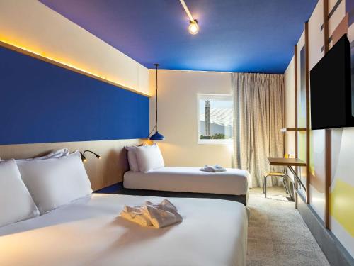 a hotel room with two beds and a tv at greet hotel Marseille Parc Chanot Velodrome by Accor in Marseille