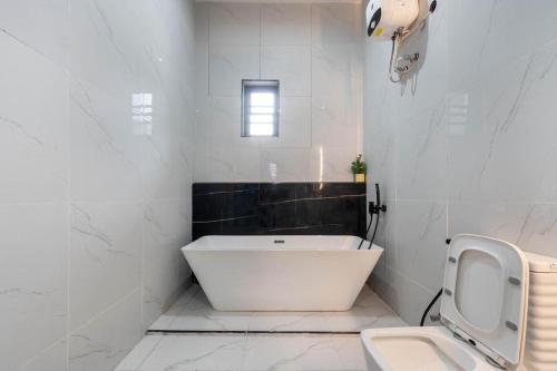 a white bathroom with a tub and a toilet at Lisa homes 2 3bedroom in Lekki