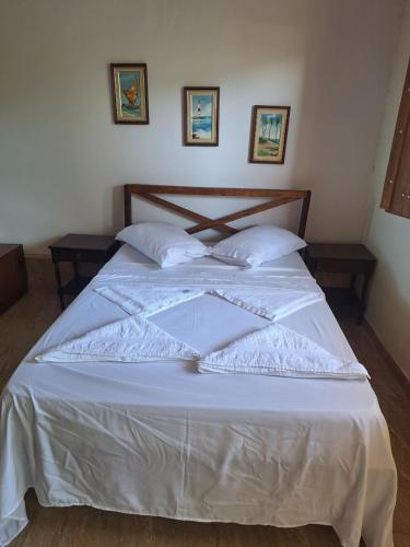 a bed with white sheets and pillows in a room at Pousada Encanto dos Olhos in Alexânia