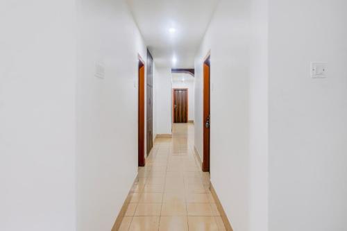 a hallway with white walls and tile floors at Super Collection O Sixmile Guwahati Formerly Hotel Gangotri in Guwahati