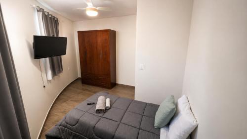 a bedroom with a bed and a tv and a couch at Casa de Hóspedes Jaú in Jaú