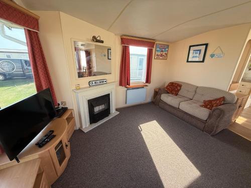 a living room with a tv and a couch and a fireplace at Bell Bank C8 - pet friendly, bed linen, close to bars and shops - Meadow Lakes Caravan & Lodge Hire in Chapel Saint Leonards