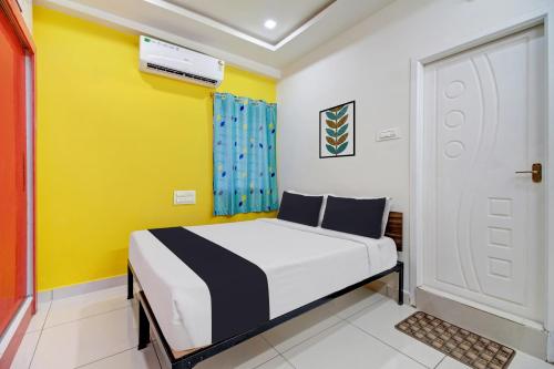 a bedroom with a bed and a yellow wall at OYO Hotel O Amaravathi Road Annapurna Nagar in Guntūr
