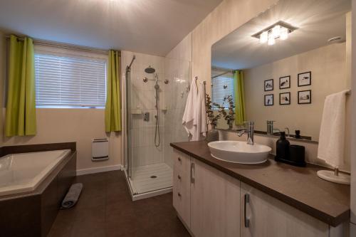 a bathroom with a sink and a tub and a shower at EdenCat Condo - Mountain View in Beaupré