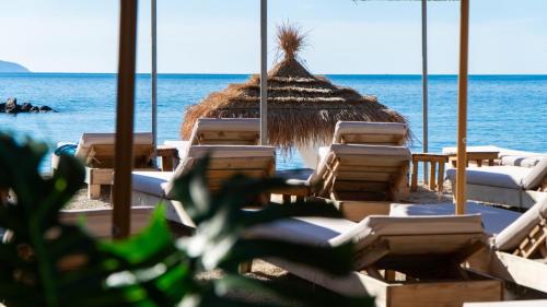 a group of lounge chairs and a straw umbrella on the beach at White Hill by Fllad e Vale in Vlorë