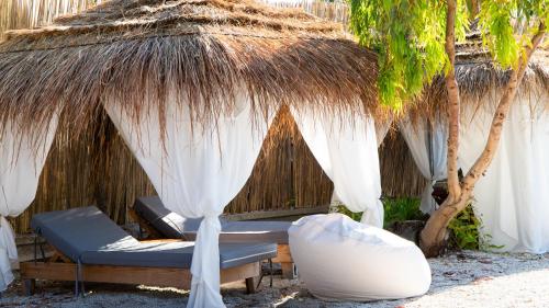 a straw hut with a bed and chairs under it at White Hill by Fllad e Vale in Vlorë