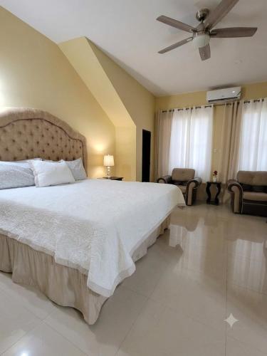 a bedroom with a large bed and a ceiling fan at dela-de rose guesthouse in Negril