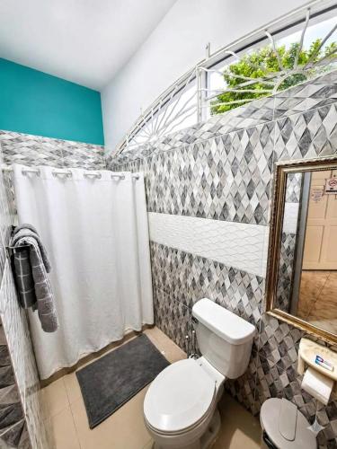 a bathroom with a toilet and a shower curtain at dela-de rose guesthouse in Negril
