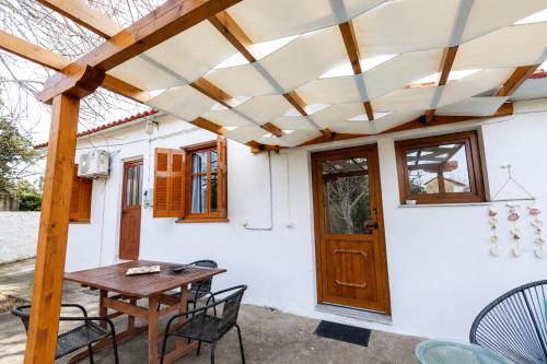 a patio with a wooden pergola and a table and chairs at SOFIA'S HOUSE No 2 in LESVOS in Apidias Lakos