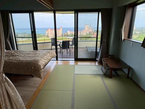 a bedroom with a bed and a balcony with a view at Villa resort -悠- in Miyakojima