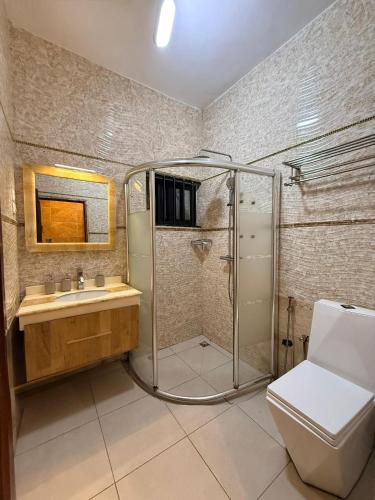 a bathroom with a shower and a toilet and a sink at RAWADE Guesthouse in Cotonou