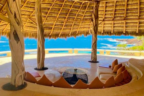 a room with a couch and a table in a straw hut at Casa Papelillo on Costa Careyes in Chamela