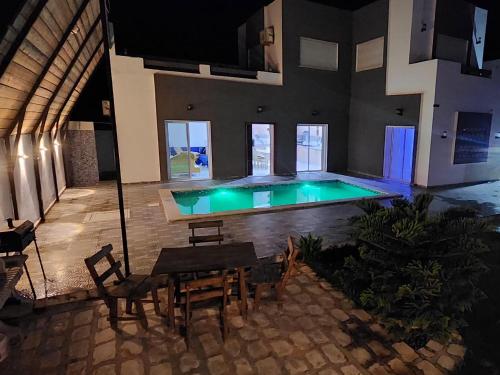 a swimming pool in a house with a table and chairs at Dar fadloun in Midoun