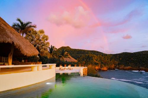 a pool at a resort with a rainbow in the sky at Casa Papelillo on Costa Careyes in Chamela