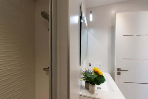 a bathroom with a sink and a vase with a yellow flower at Infinity House. Ocean View hot tub. in Adeje