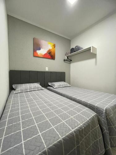 ein Schlafzimmer mit zwei Betten und einem Gemälde an der Wand in der Unterkunft Apto do Xavier in Juazeiro