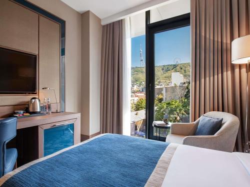 a hotel room with a bed and a large window at Tbilisi Philharmonic Hotel by Mercure in Tbilisi City