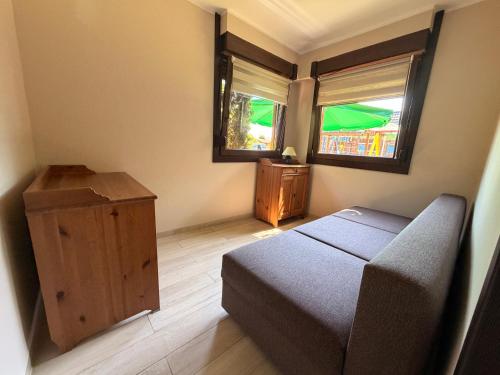 a small bedroom with a bed and two windows at Zefir Domek nr 5 in Dąbki