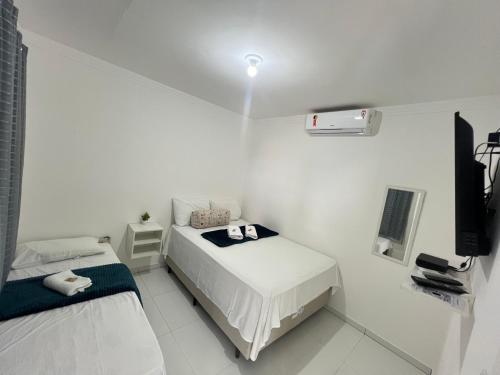 a white room with two beds and a television at Kitnet em Santo Antônio in Mata de Sao Joao