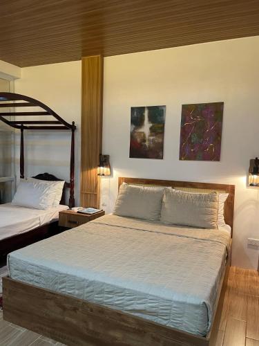 a bedroom with two beds and two paintings on the wall at Casa De Española Hotel and Resort in Aritao