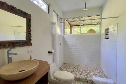 a bathroom with a sink and a toilet and a mirror at Casa Siwa in Cahuita