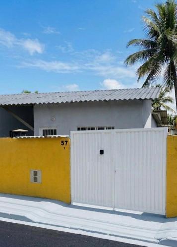 a white and yellow house with a white garage at Casa Bali Beira Mar - Sesc Bertioga in Bertioga