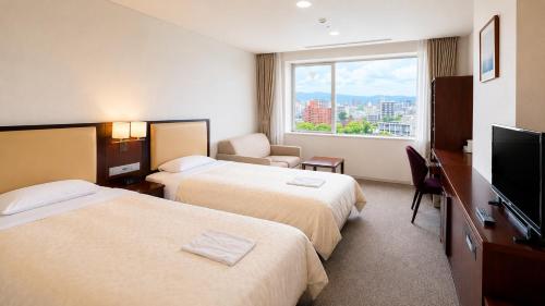 a hotel room with two beds and a flat screen tv at Hotel Mielparque Kumamoto in Kumamoto