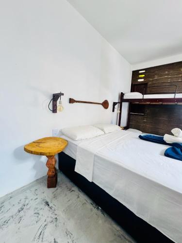 a room with two beds and a wooden table at Maré de Atins Eco Lodge in Atins