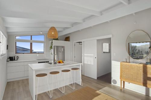a white kitchen with a counter and a mirror at Tideview Cottage - Incredible Views - Tairua in Tairua