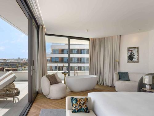 ein Schlafzimmer mit Badewanne und großem Fenster in der Unterkunft SLS Barcelona in Barcelona