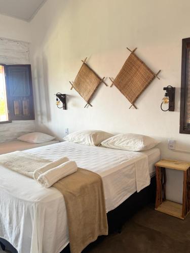 a bedroom with a large white bed with towels on it at Maré de Atins Eco Lodge in Atins