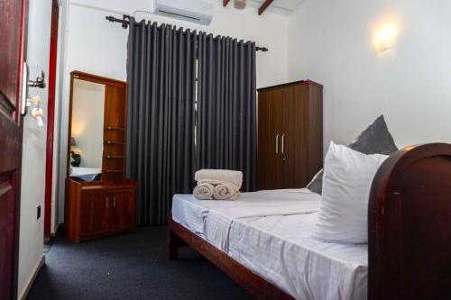 a bedroom with a bed with white sheets and a mirror at Hidden Heaven Grove-Kandy in Kandy