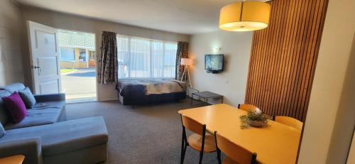 a living room with a couch and a bed and a table at Aalton Motel in Christchurch