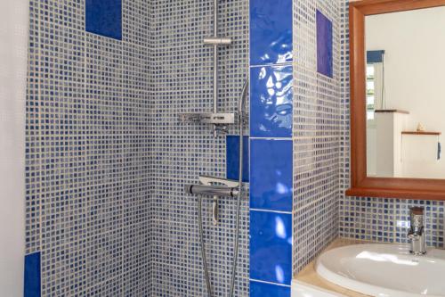 a blue tiled bathroom with a sink and a shower at Combava à Marie Galante in Grand-Bourg