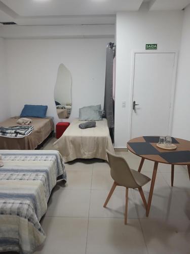 a room with two beds and a table at COLOFT - Studio Térreo com Acessibilidade in Anápolis