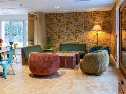 a living room with chairs and a table and a tableablish at greet Hotel Chatellerault in Châtellerault
