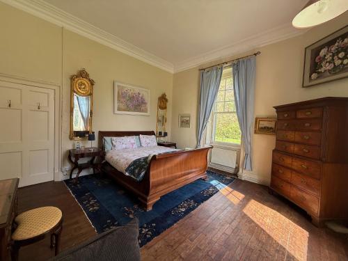 a bedroom with a bed and a dresser and a window at Shannon River House & Gardens in Limerick