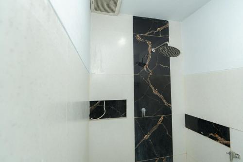 a bathroom with a shower with black marble tiles at Heyho Homestay Maluk in Maluk